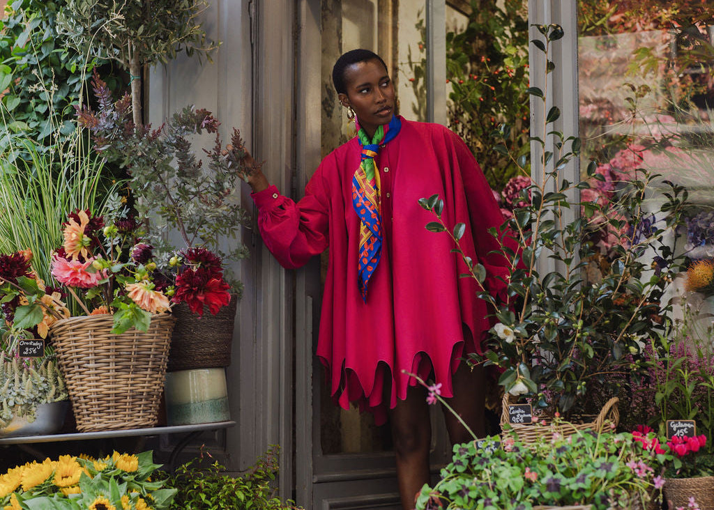 Elise in Pink Sestra standing in a flower shop surrounded by flowers and plants.